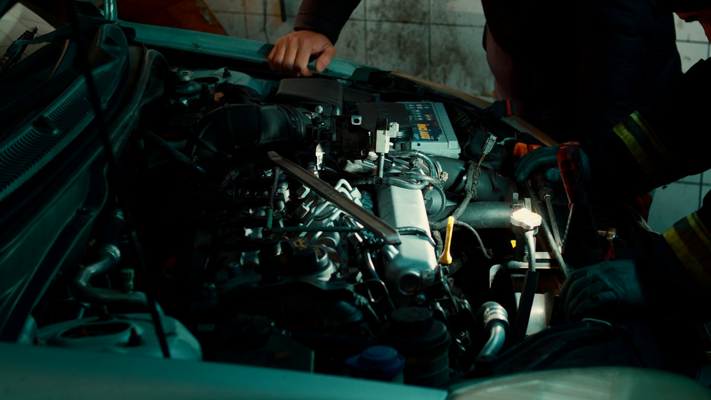 Mechanikerhände, die in einer Werkstatt an einem Automotor arbeiten.